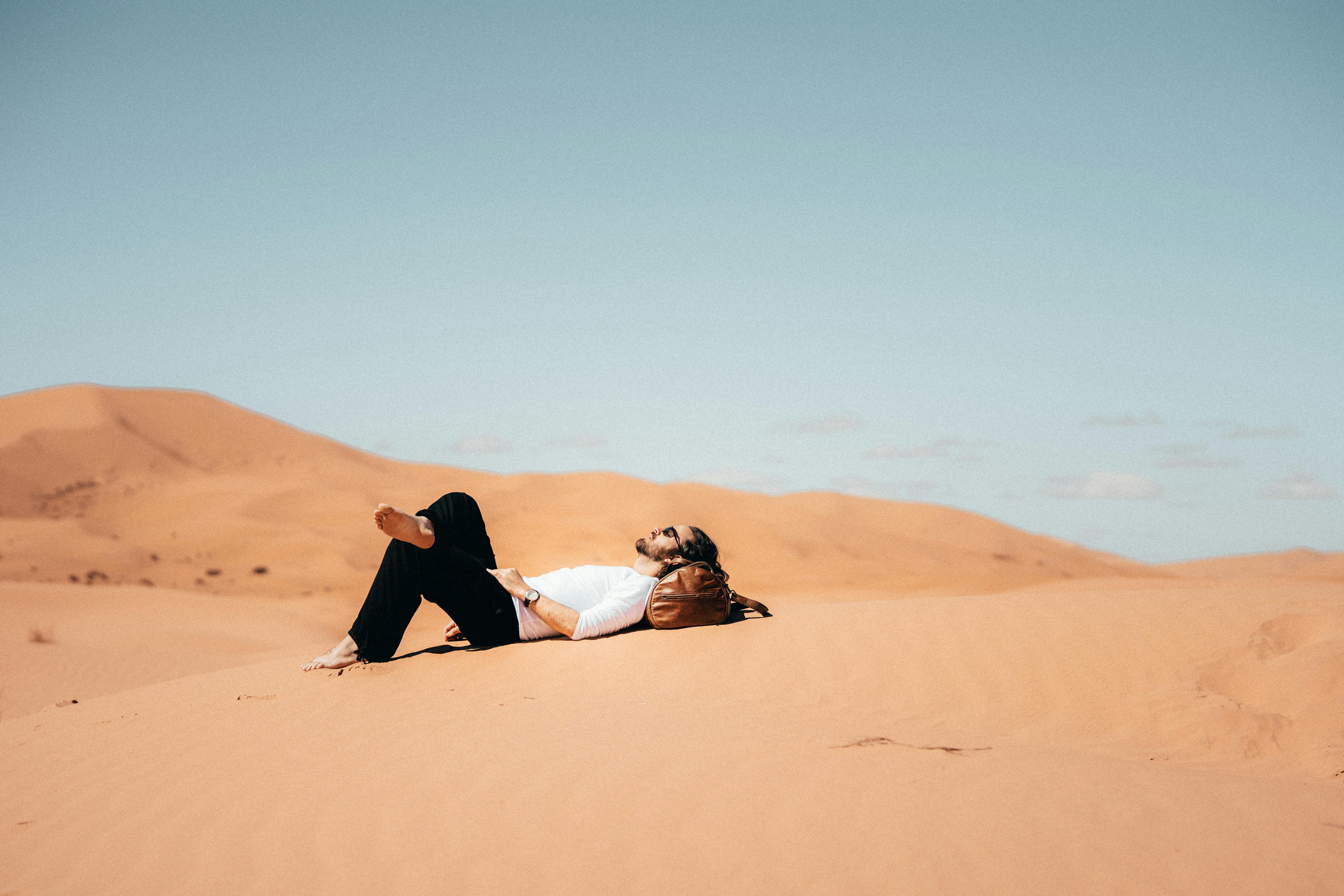 Free Woman in Black Dress Sitting on Brown Sand Stock Photo